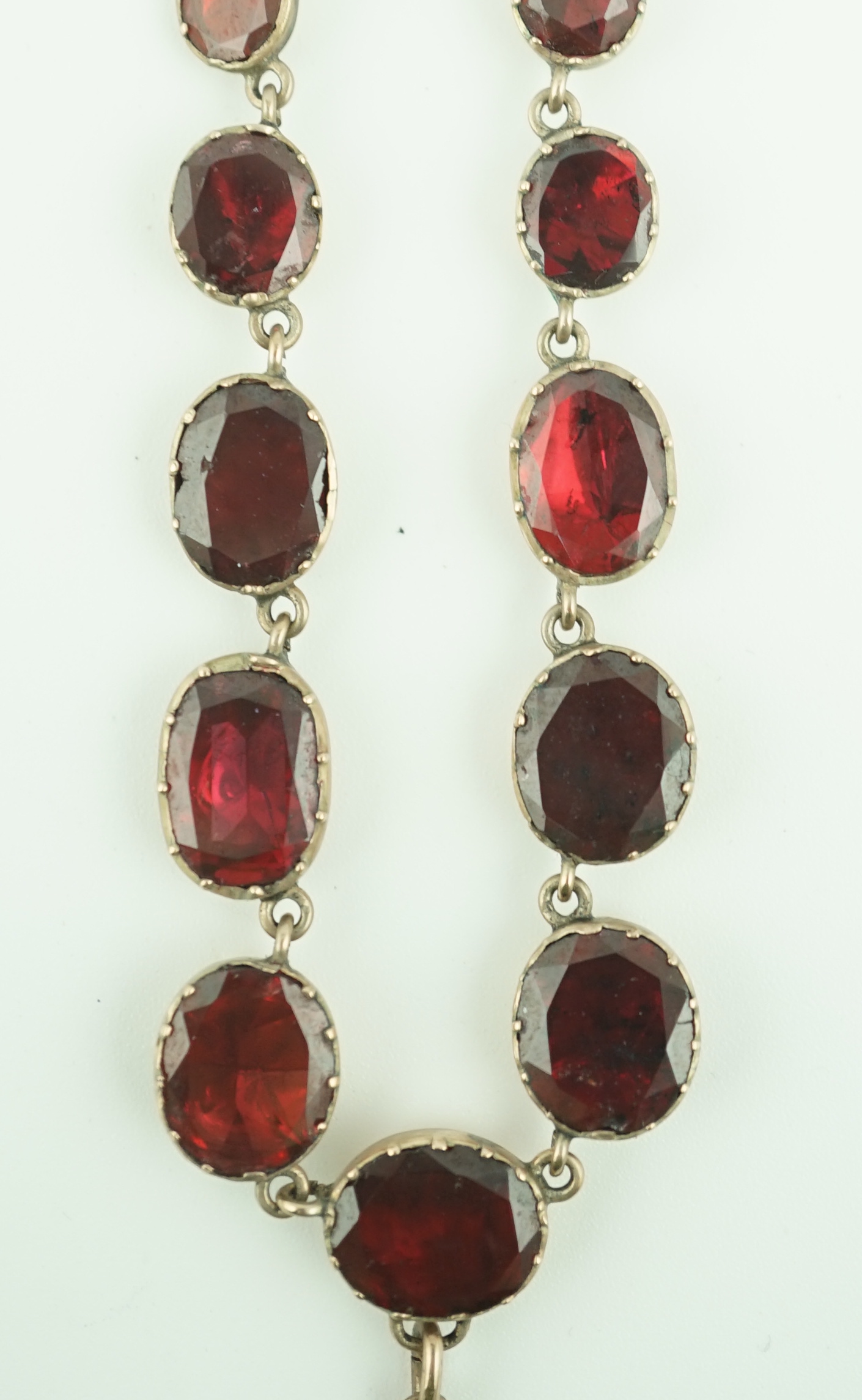 An early 19th century gold, and thirty five graduated foil backed garnet set necklace, with later garnet and seed pearl set drop
